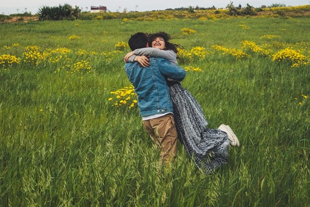 Imagen de una pareja que se abraza en medio de un campo de girasoles