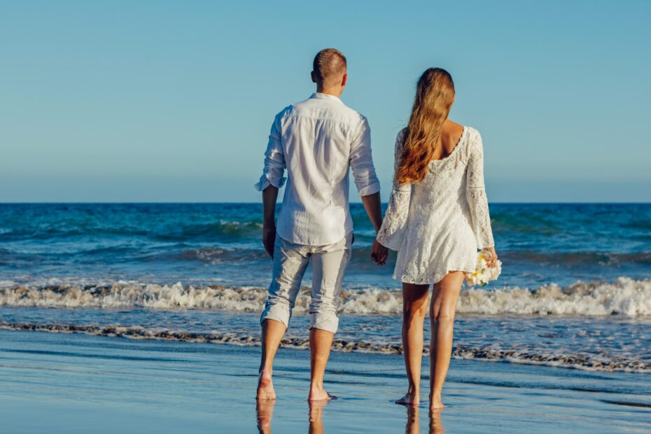 Imagen de una pareja caminando por la playa tomados de la mano