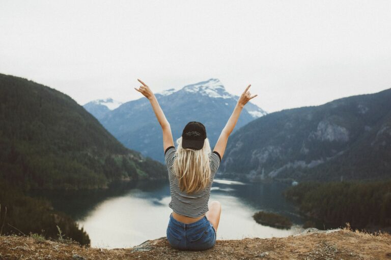 Imagen de una mujer sentada frente a un lado y montañas