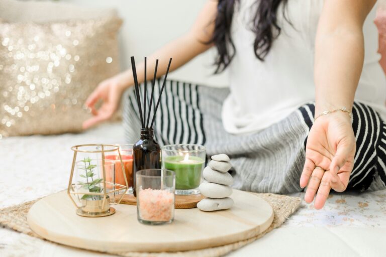 Imagen de una mujer sentada meditando con unas velas y baritas aromáticas